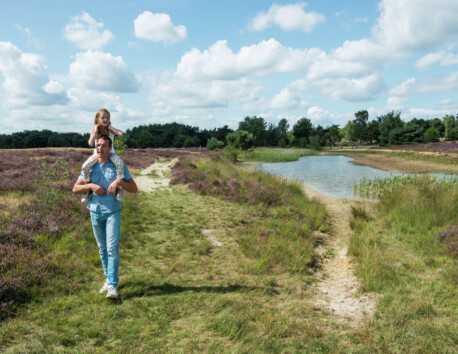 Vater und Tochter spazieren auf dem Fußweg durch das Moor am Teich entlang