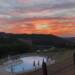 Zwembad met ligstoelen parasols en uitzicht over de heuvels van Umbrië Casa & Glamping Sorriso zonsondergang