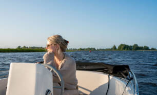 Vrouw vaart op boot Nationaal Park Weerribben – Wieden op Watersportcamping Tussen de Diepen