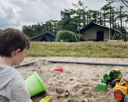 a child playing in a sandbox with various toys