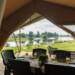Uitzicht op rivier de Maas vanuit safaritent met gedekte eettafel op Camping de Boomgaard