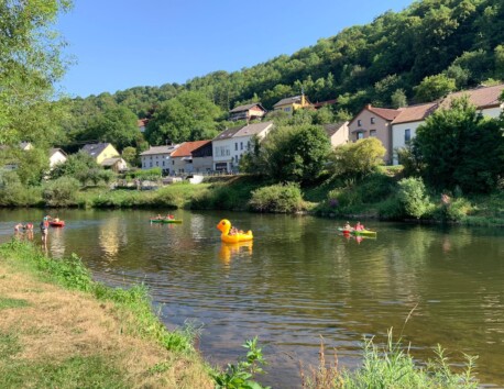 Kinderen op het water aan het spelen in kano's en op een opblaasbare eend op de Sure
