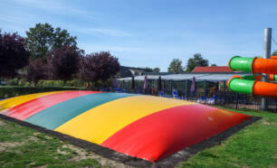 Sprinkussen met daarachter overdekt zwembad met glijbaan Camping 't Veld